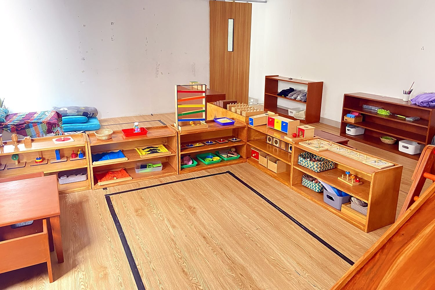 Ruang kelas dengan sudut istirahat dan rak mainan Montessori